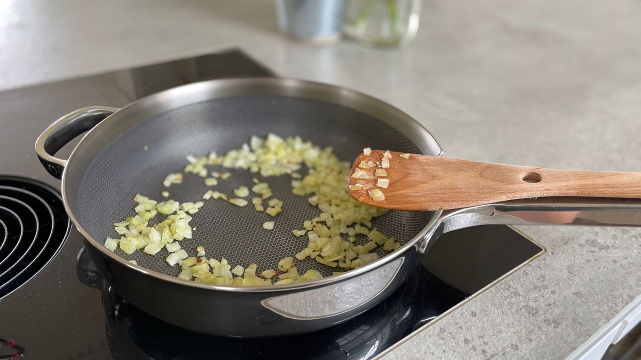Diced onions frying in Our Place's new Titanium Always Pan on an induction hob