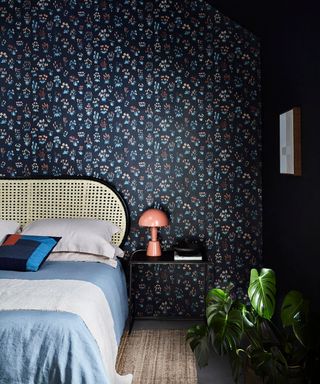 dark wallpapered bedroom with light blue bedding and rattan bed