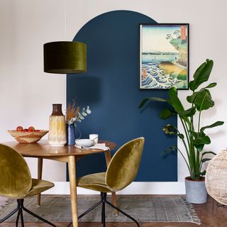 dining area with blue painted arch and dining table with chairs and painting on wall