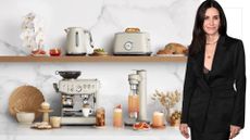 A cutout of Courteney Cox next to the Sage Barista Express Impress on a coffee station with a marble background