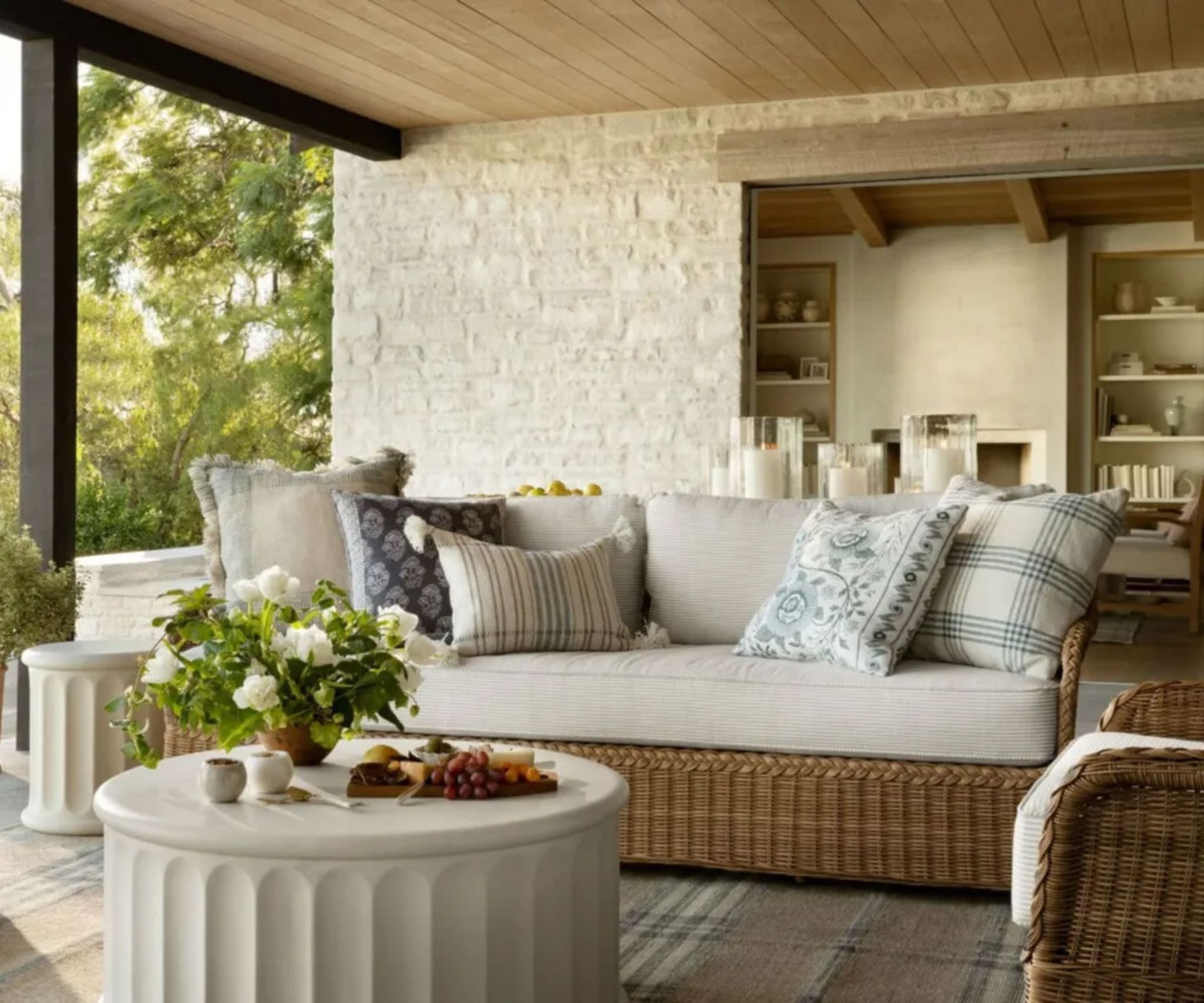 mcgee and co outdoor collection patio under a roof with a rug, wicker sofa, coffee table and printed cushions