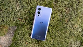 La parte trasera de un OnePlus 9 boca abajo sobre el césped.