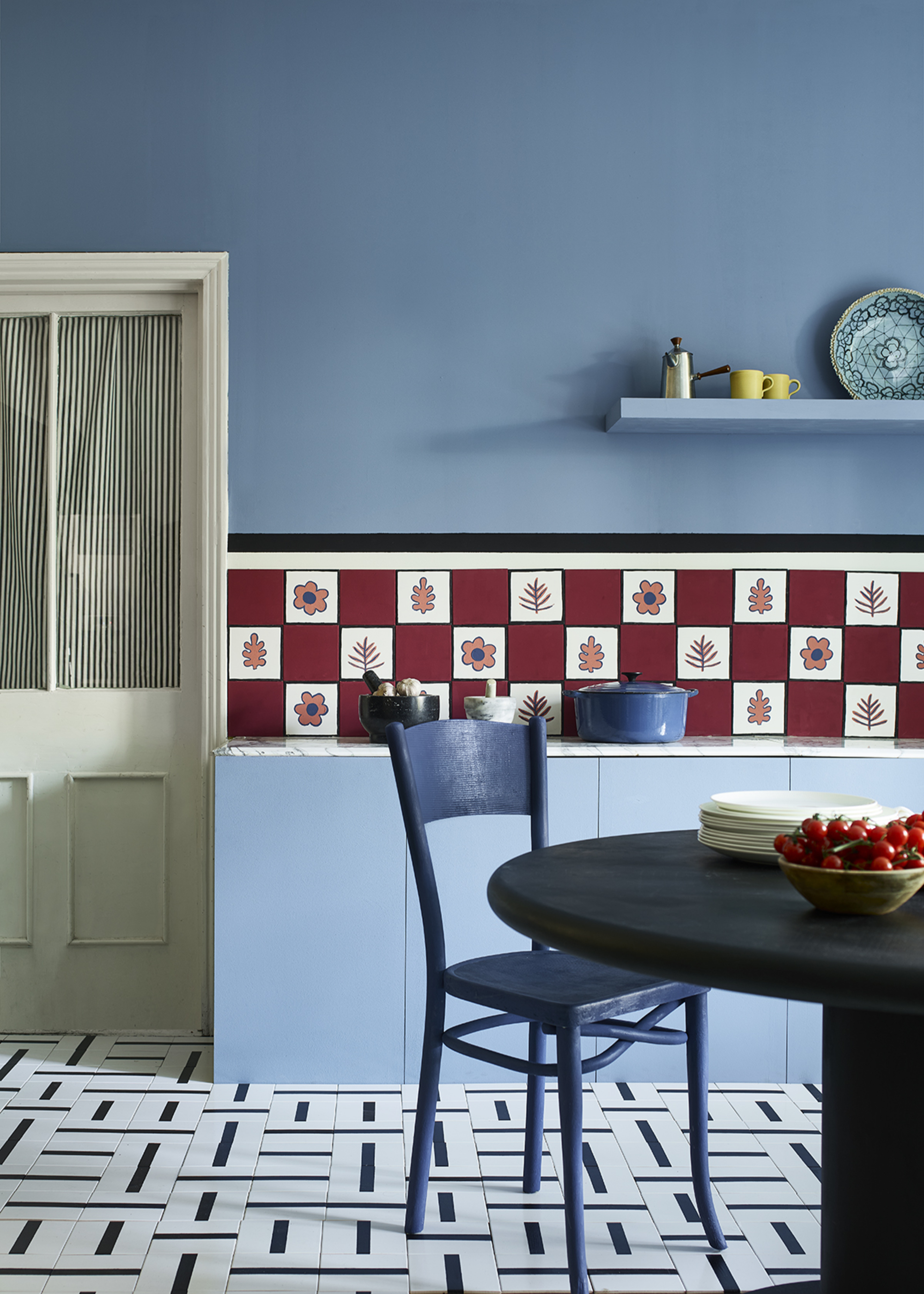 colorful kitchen tiles in red and white with blue cabinets and walls and graphic printed floor tiles