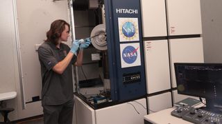 University of Arizona scientists have received a small portion of the asteroid Bennu sample and analysis has begun in their lab. Doctoral student Lucas Smith loads a Bennu sample into an electron microscope for analysis.