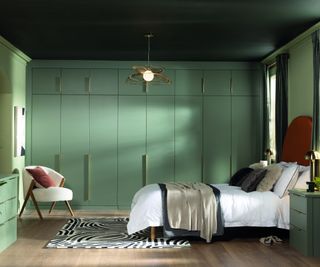 modern green fitted wardrobes in bedroom with wooden floor and bed