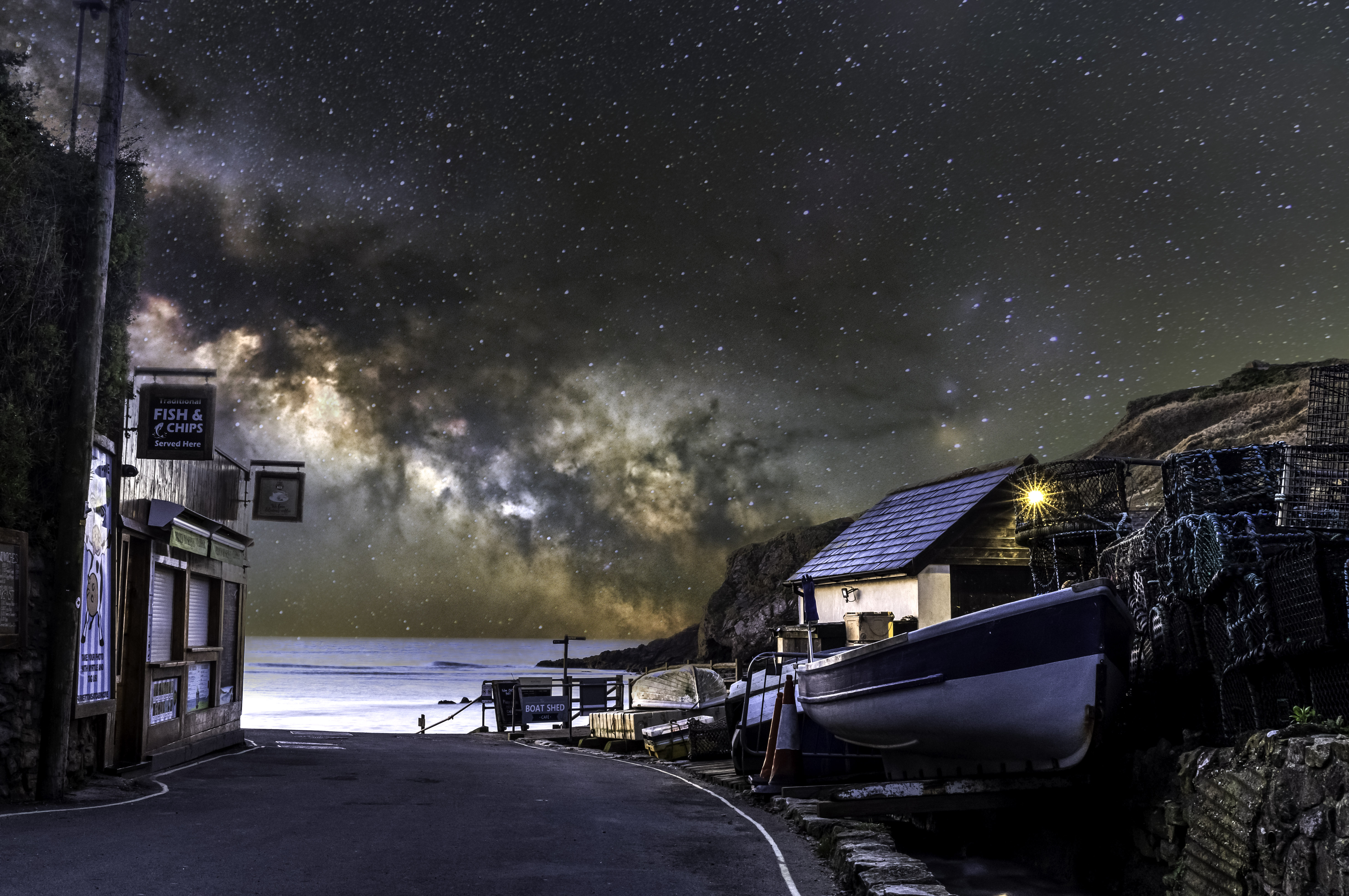 A photo of the Milky Way galaxy in the night sky sits behind scenes from a fishing village