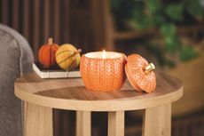 Hotel Collection Fall Icon candle in pumpkin-shapped knitted effect orange vessel on side table