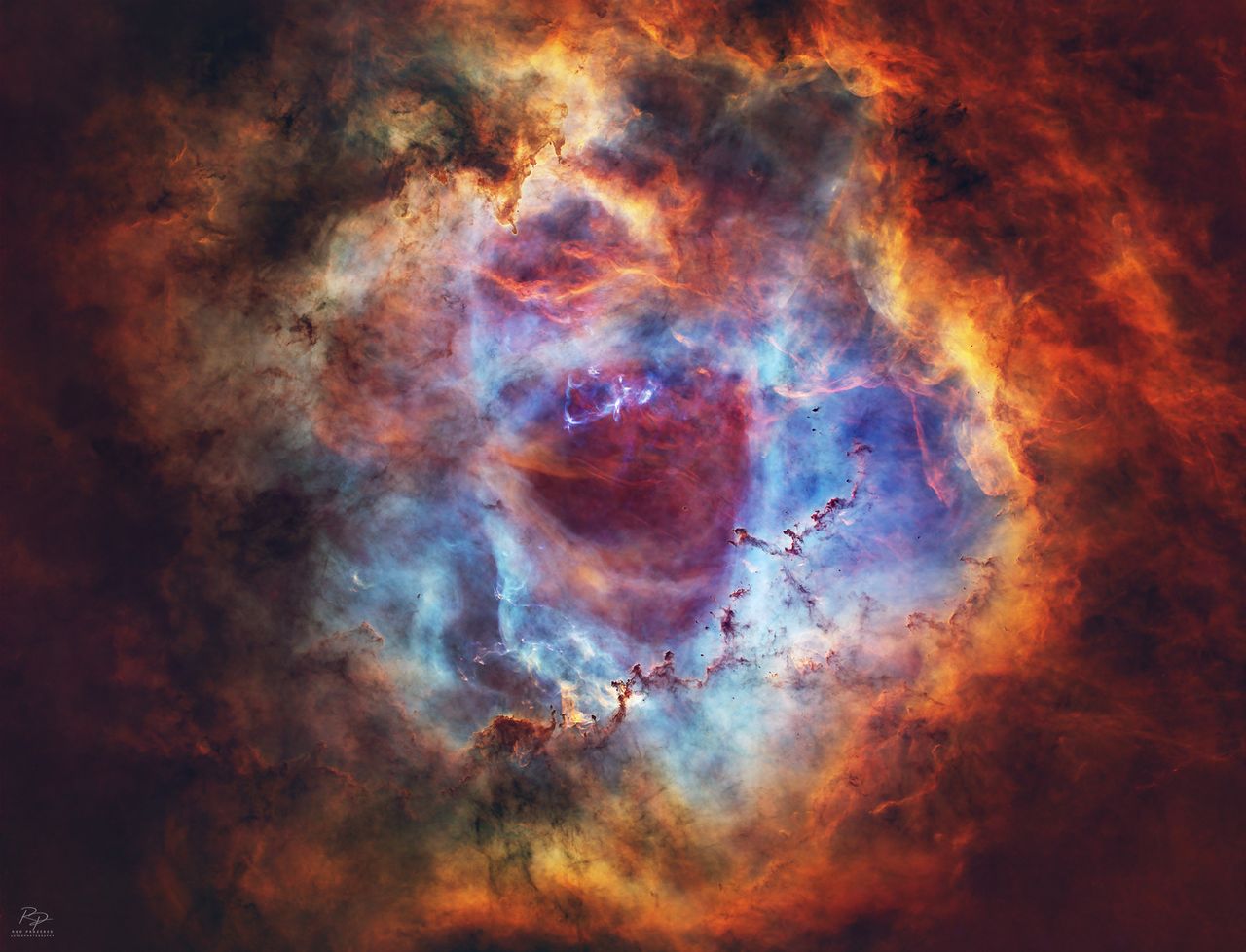 A deep space nebula scene is shown, featuring swirling masses of colorful interstellar gas and dense, dark dust filaments.