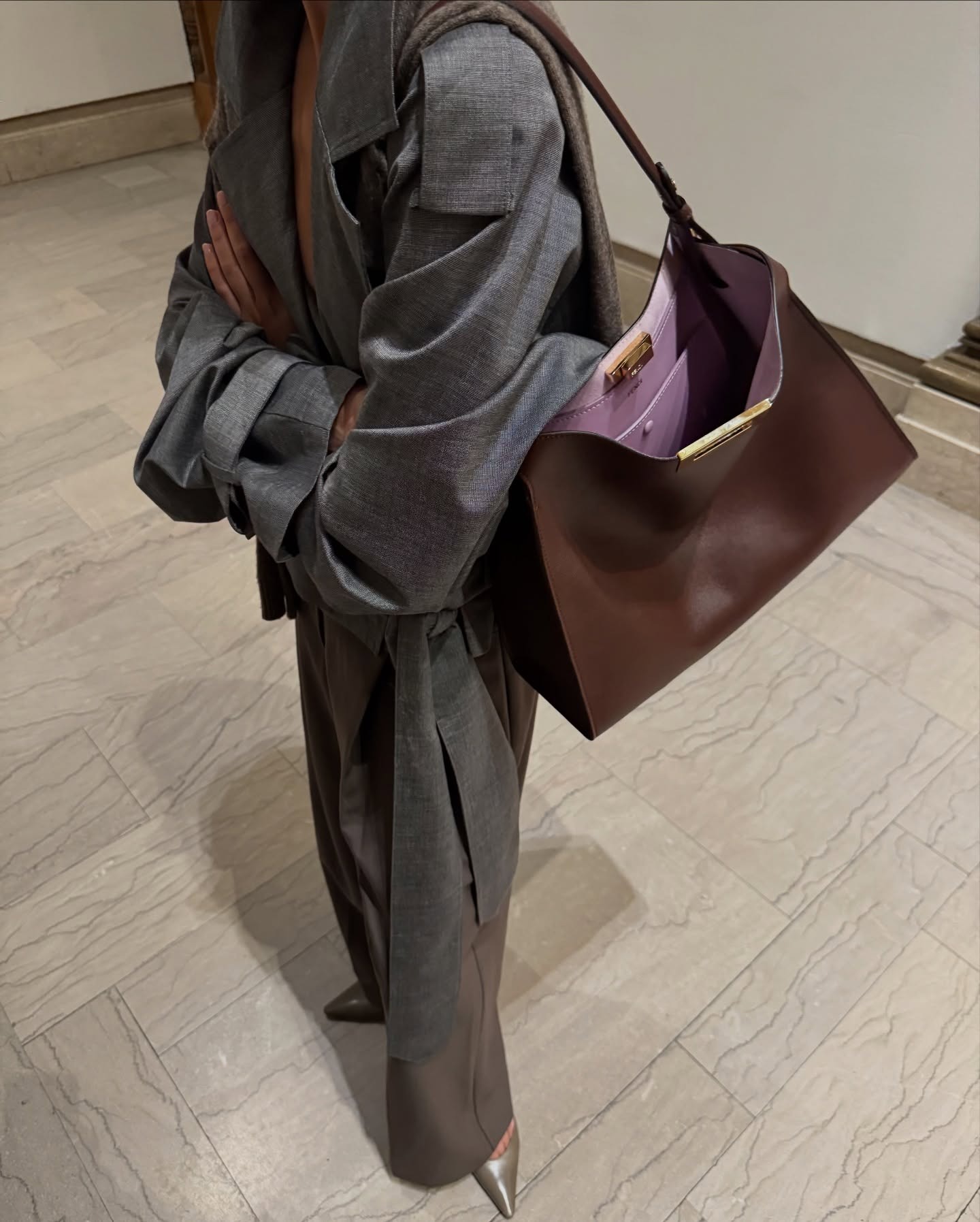 Andrea wears a gray jacket, brown fendi bag and gray trousers.