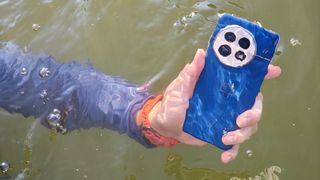 Holding the blue OnePlus 13 under water in a lake