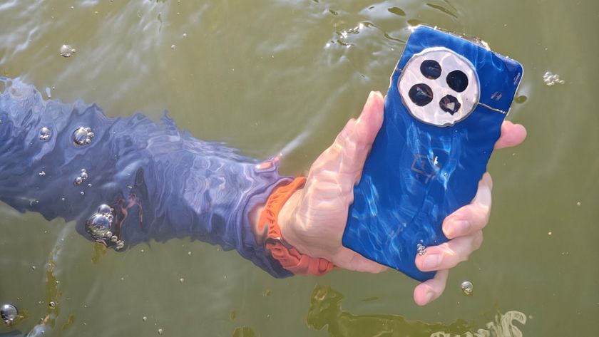 Holding the blue OnePlus 13 under water in a lake