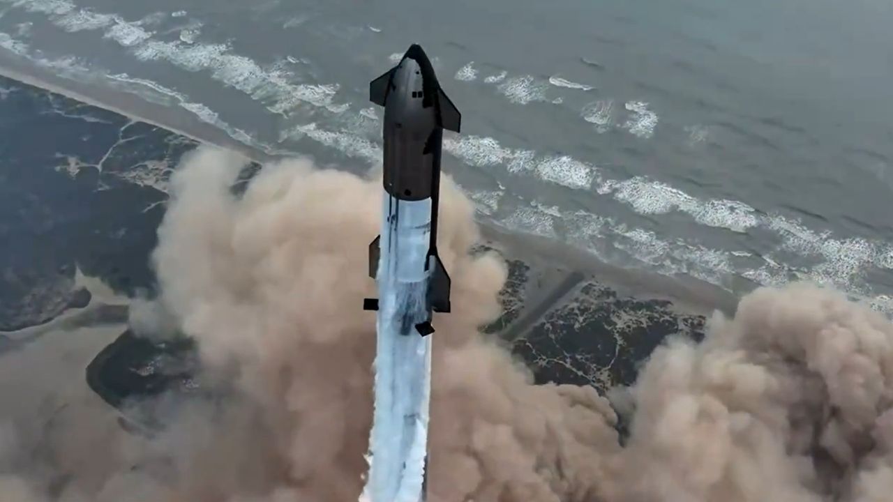 a large silver-and-black rocket launches above a plume of fire