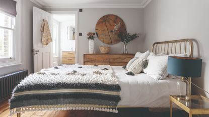 A bedroom with a symmetrical set-up, white bedding, cream wall panelling and matching wiggly table lamps