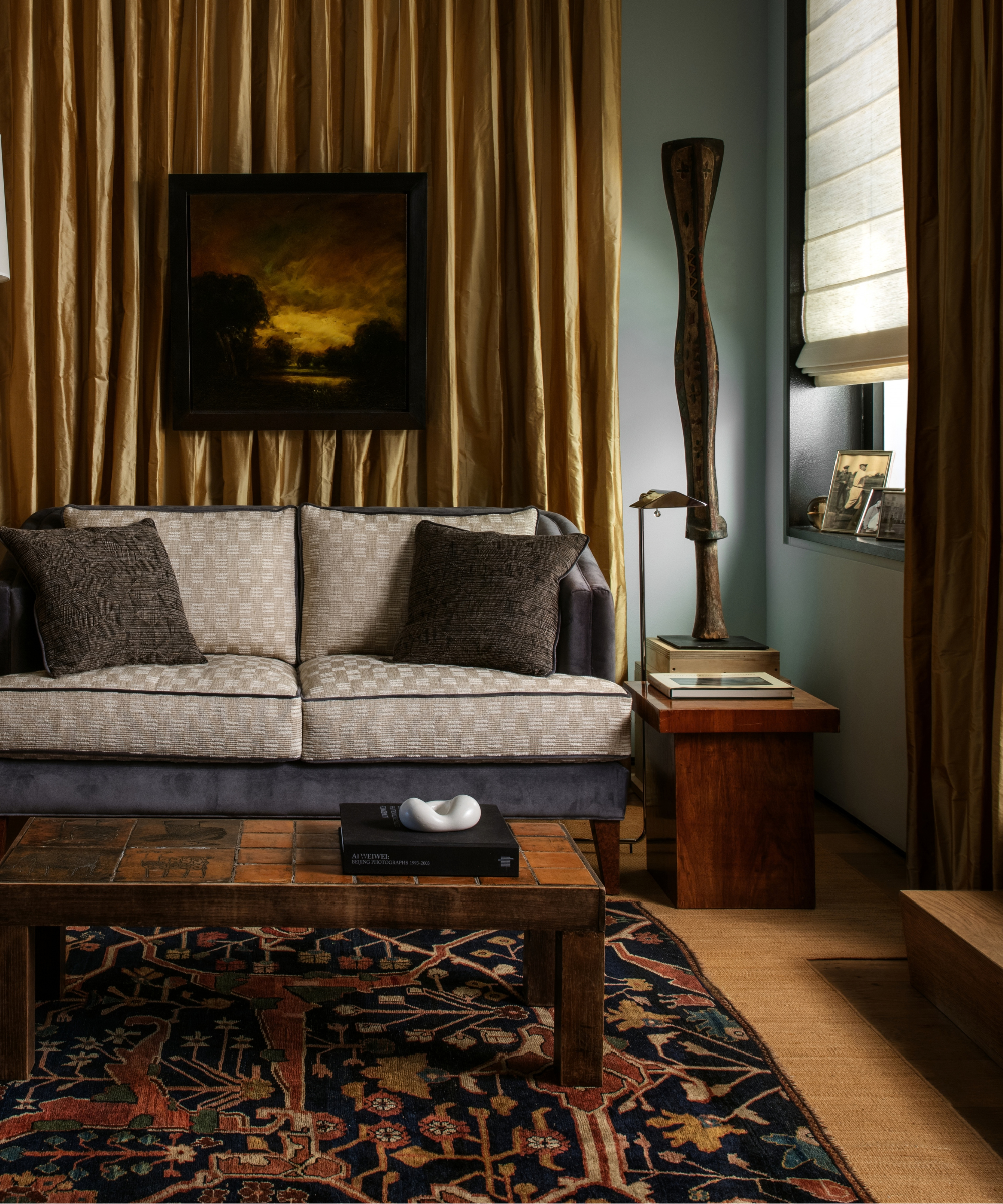 Opulent sitting room featuring a small, moody antique rug layered overtop a larger natural fiber one
