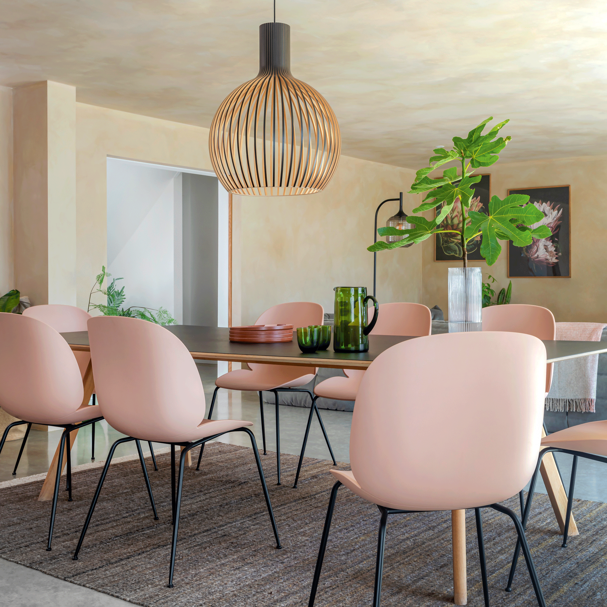 open plan living dining area with a dining table and pink dining chairs and a Ligne Roset sofa set in Grey