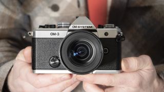 OM System OM-3 mirrorless camera in the hand, 12-45mm F4 lens attached