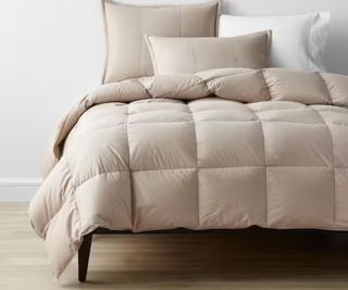A warm brown comforter on a bed with white sheets.