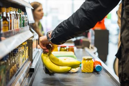 Person Putting Bananas On Conveyor At Store Checkout
