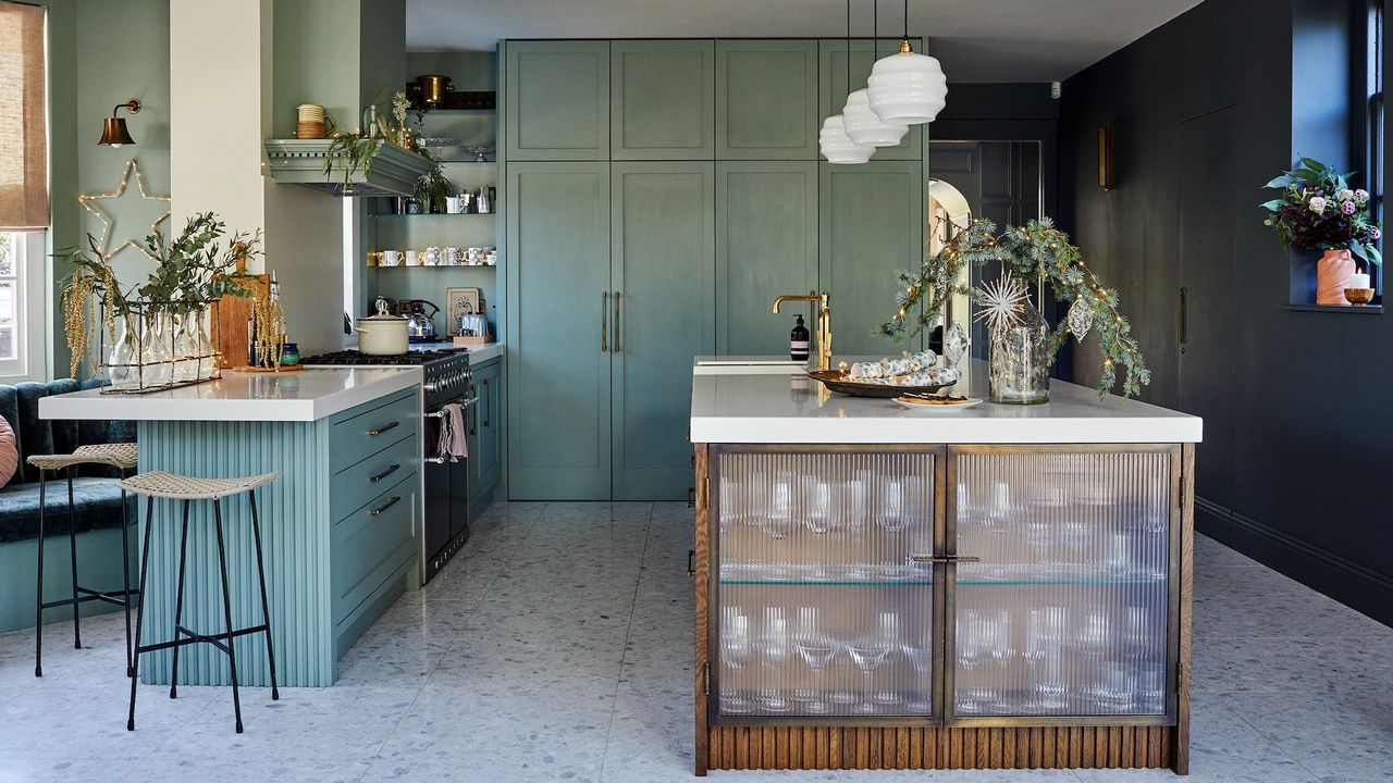 Open plan kitchen with green/blue interior and a large island with stools 