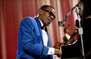 jamie foxx wearing a blue suit and sunglasses and playing the piano in the movie ray