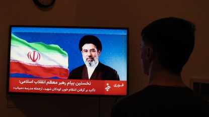 Man watches Iran TV's statement from new leader Ayatollah Mojtaba Khamenei
