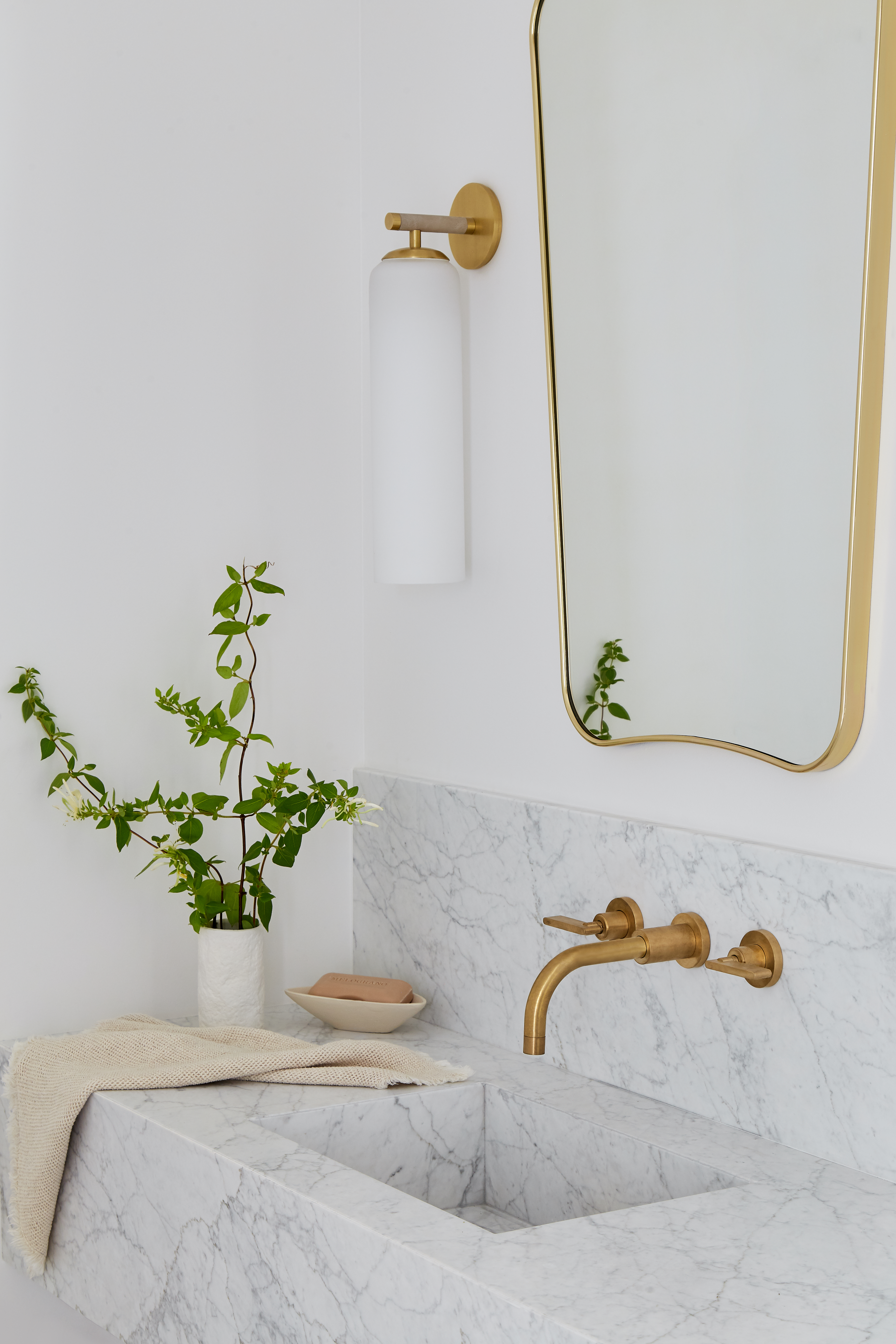 a white bathroom with a gio ponti mirror by gubi above