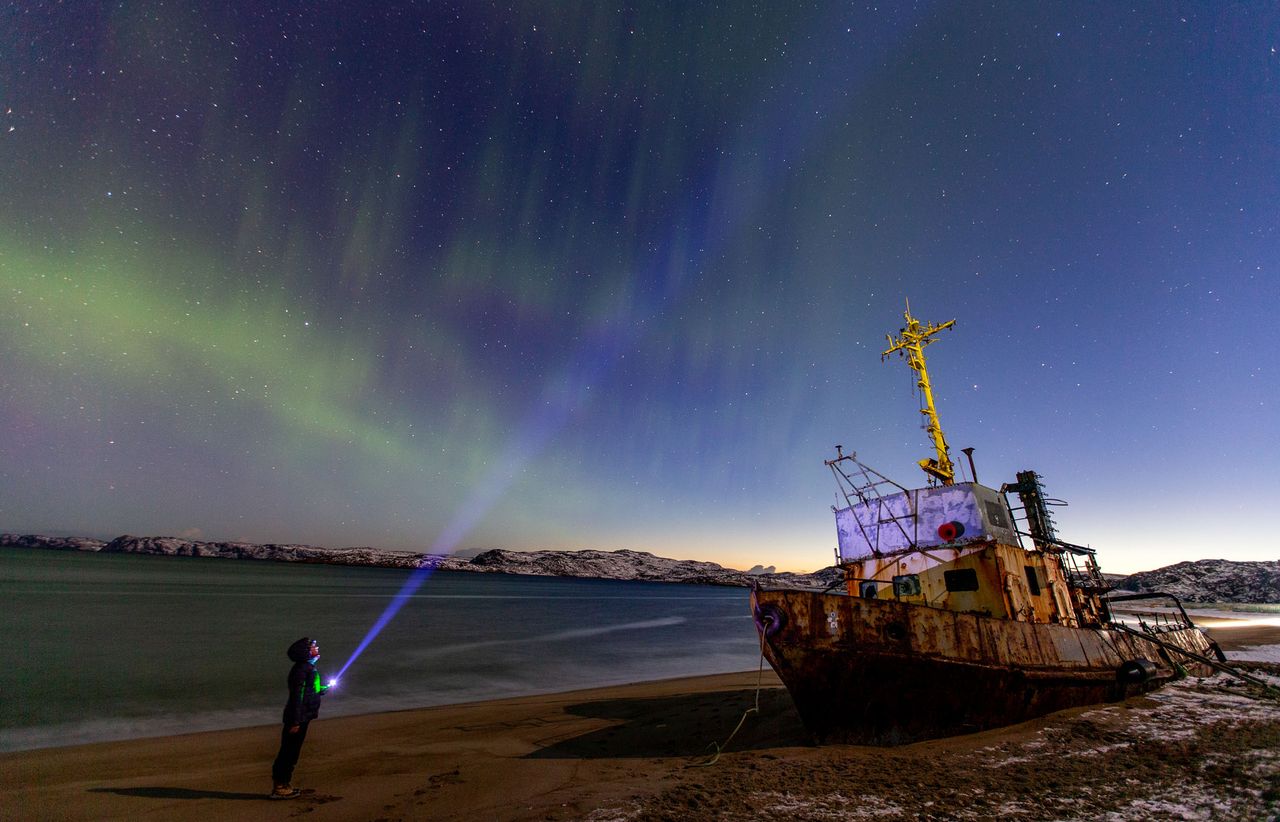 A tourist views the northern lights over Teriberka, Russia, a village of about 1,000 people about 120 km away from the city of Murmansk on the Russian Arctic coast, on Oct. 30, 2021 during a geomagnetic storm caused by a solar flare on Oct. 28..