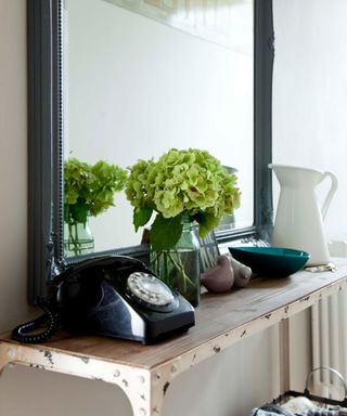 vase of flowers on console table with telephone