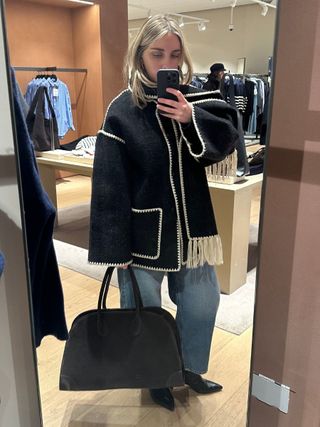 Woman wears scarf coat, blue jeans and suede bag