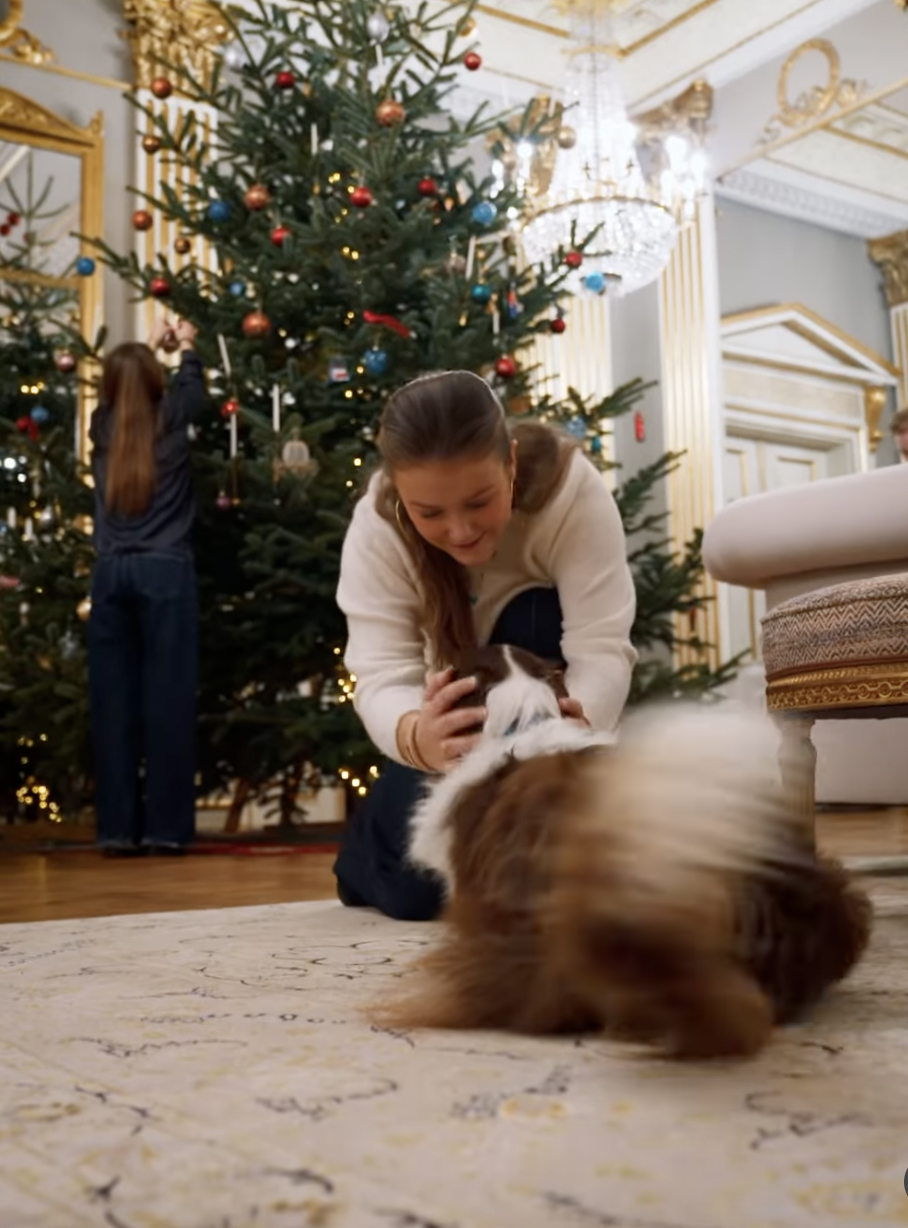 Princess Isabella petting a dog in front of a Christmas tree