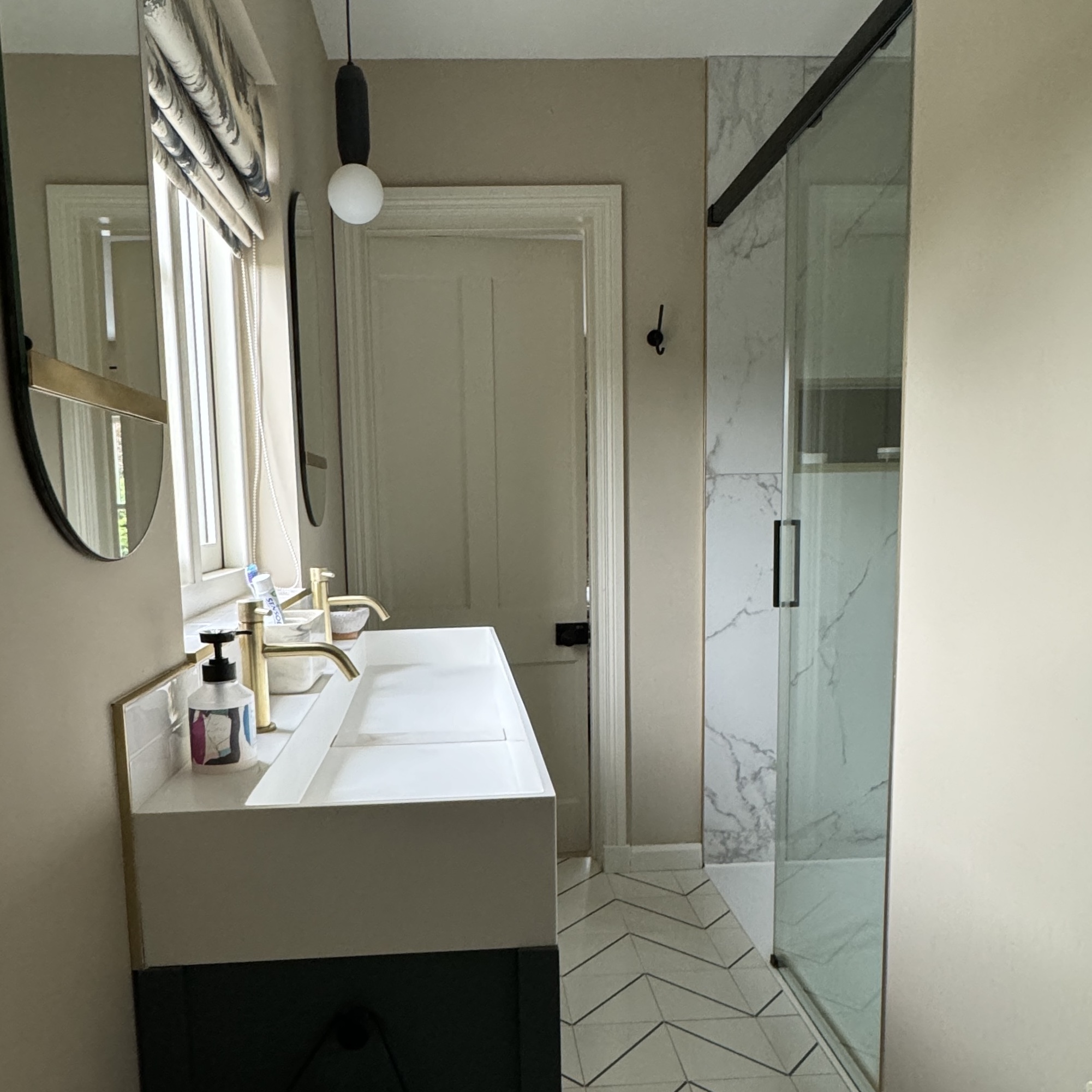 narrow en-suite with sliding shower enclosure, double vanity and zig zag floor tiles