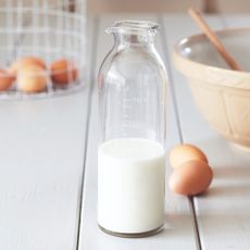 A bottle of milk with eggs around it