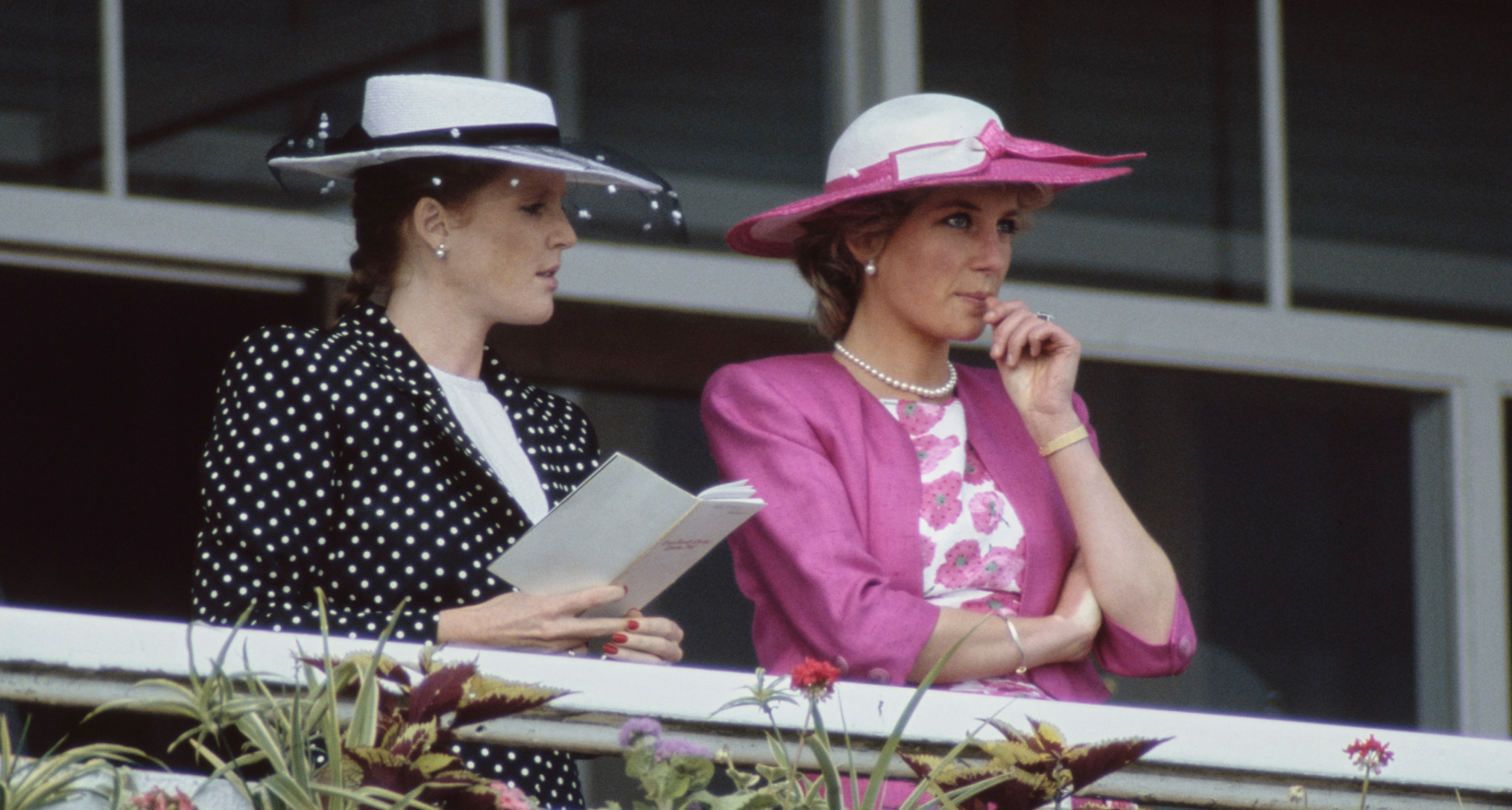 Sarah Ferguson and Princess Diana wearing hats standing along a railing at the Epsom Derby