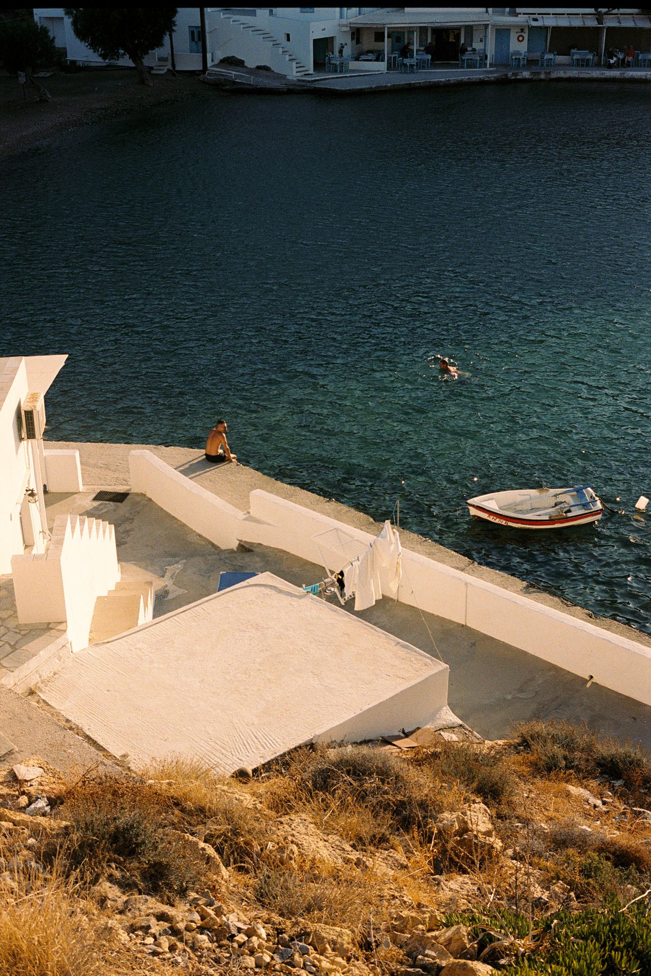 The island of Sifnos, swimmer sits beside water in harbour