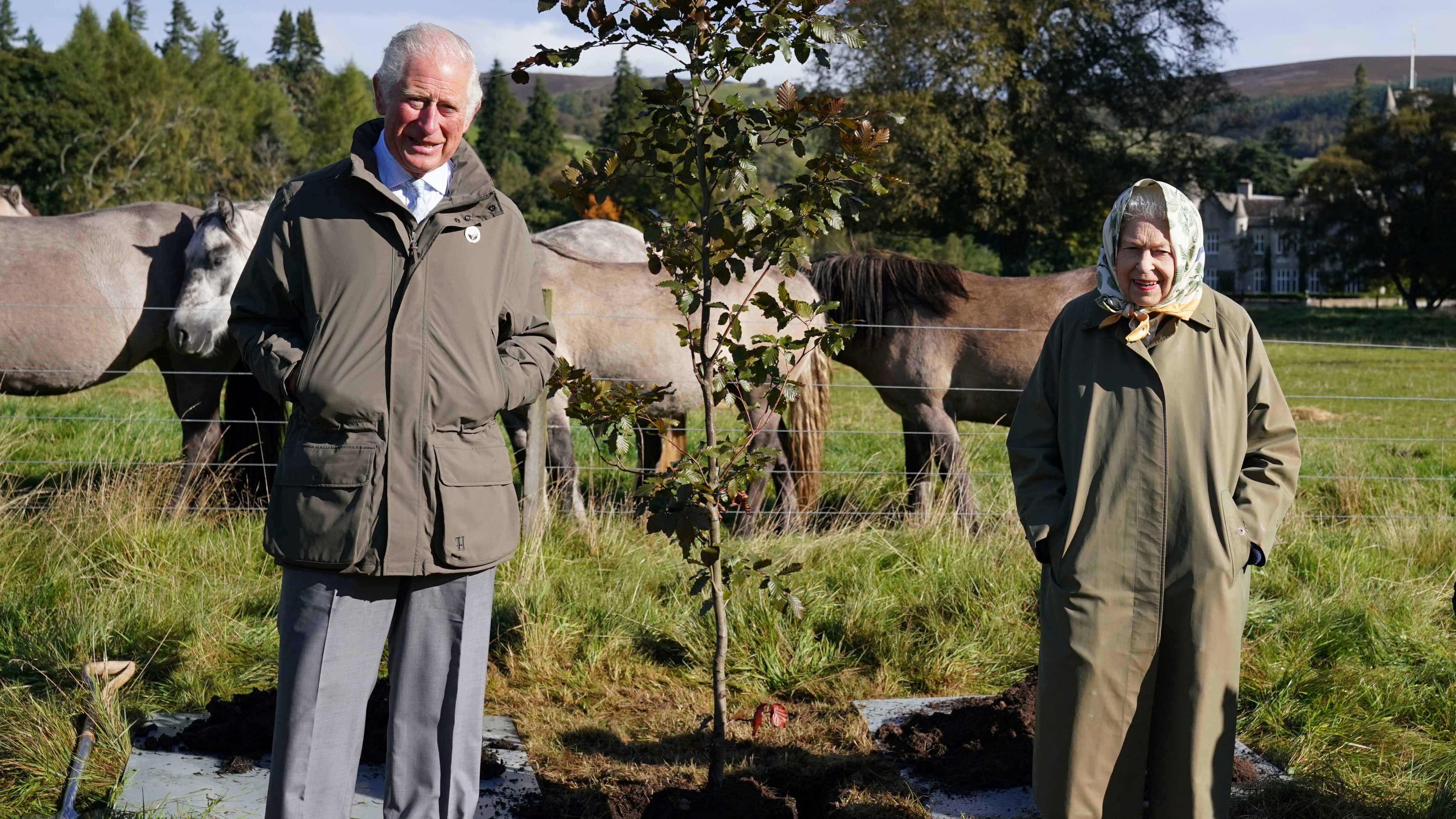 Queen Elizabeth and King Charles pose alongside the tree which they planted to mark the start of the official planting season for the Queen's Green Canopy (QGC) at the Balmoral Cricket Pavilion, Balmoral Estate in Scotland on October 1, 2021