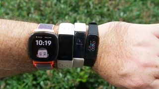 Left to right: Fitbit Sense, Charge 3, Inspire 2, and Luxe trackers worn in one hand