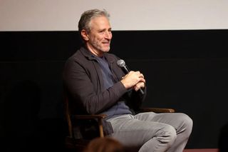 Jon Stewart holds a microphone