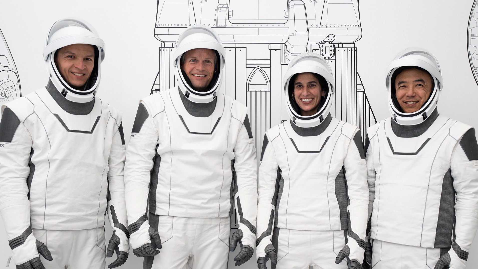 Top Stories Tamfitronics four astronauts standing in a row in spacesuits, smiling. a line drawing of a rocket is behind them