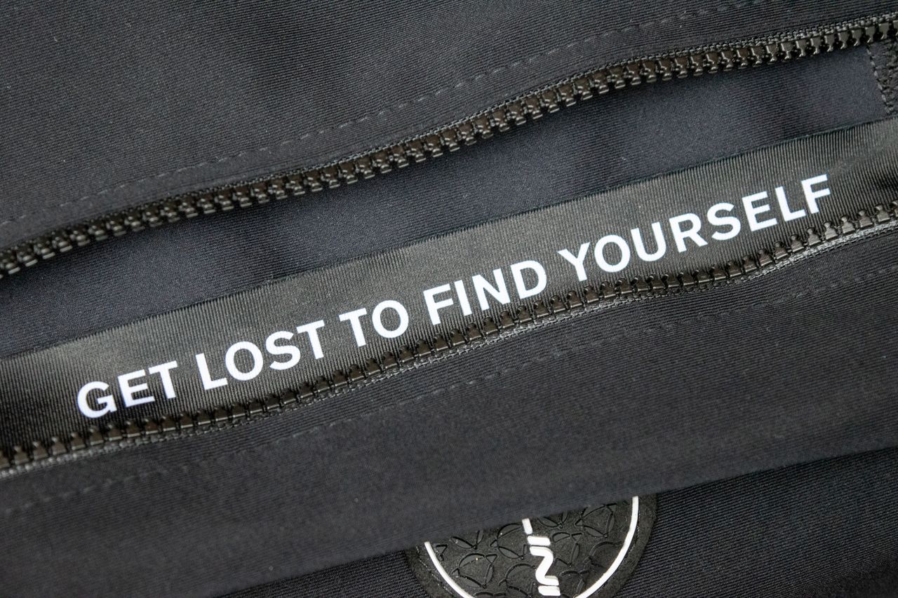 The gilet zipper guard with 'get lost to find yourself' printed on