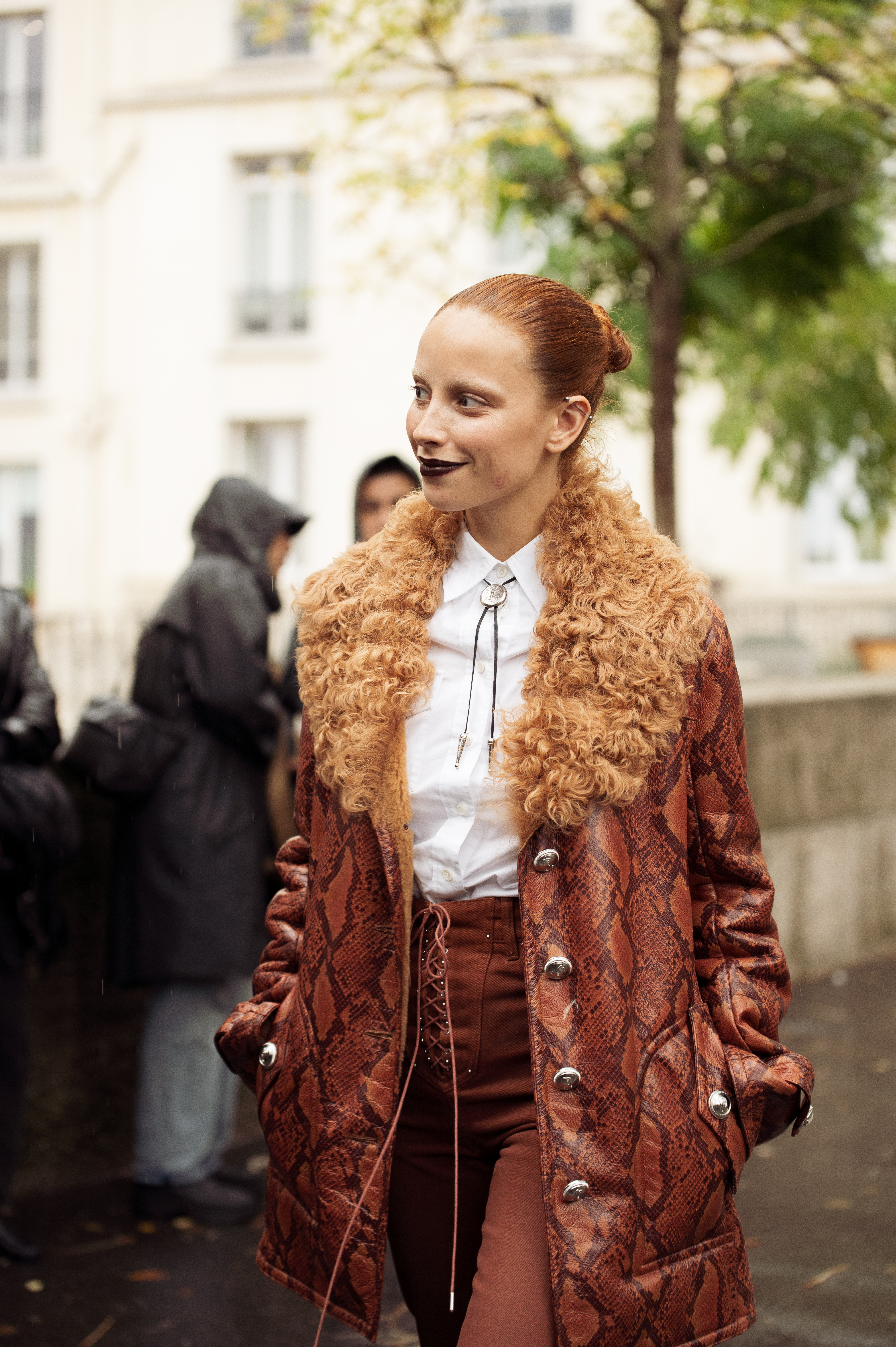 Marie Gaguech wears brown pants, white shirt, metal accessory tie, brown leather coat with fur collar outside The Paco Rabanne show during Womenswear Spring/Summer 2025 as part of Paris Fashion Week on September 25, 2024 in Paris, France.