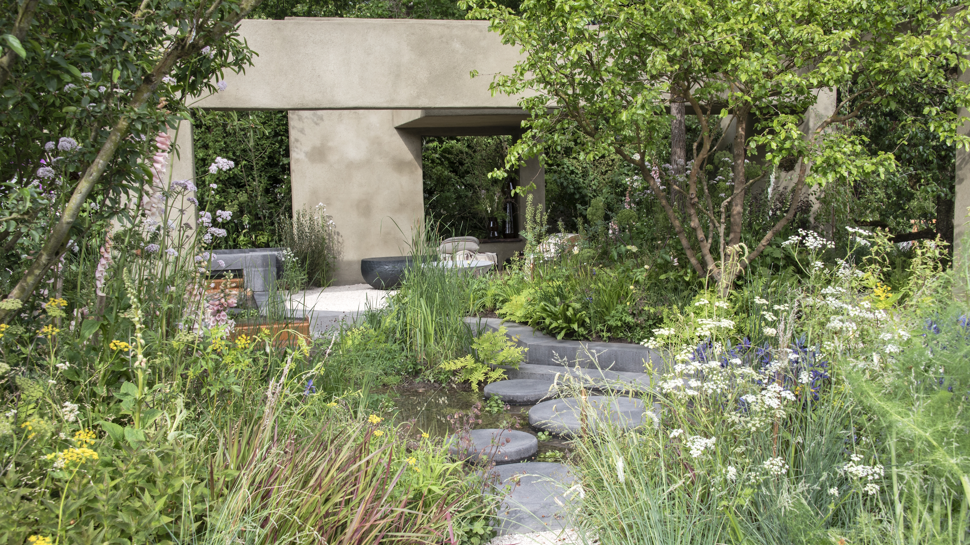 Packed herbaceous borders in bloom and a stone seating area at the Chelsea Flower Show 2026