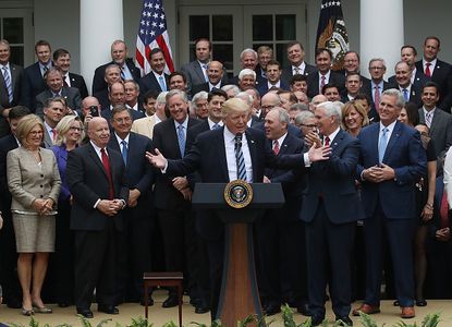 President Trump speaks with House Republicans behind him.