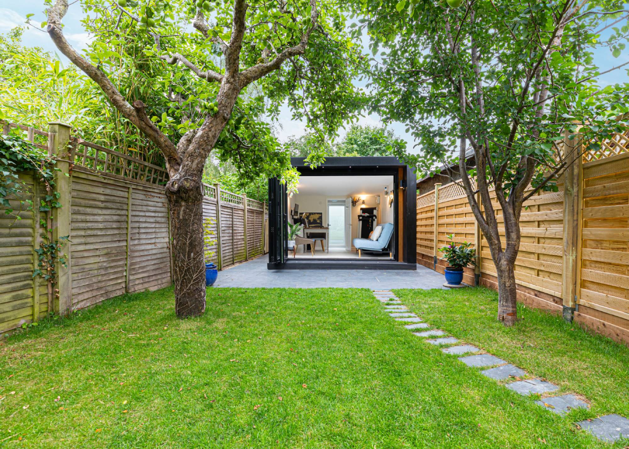 garden room at end of lawn with trees either side