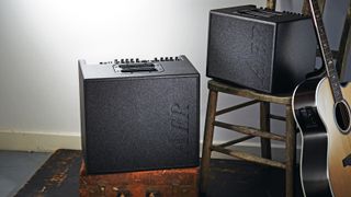 Two AER acoustic guitar amps with an acoustic guitar leaning on a chair