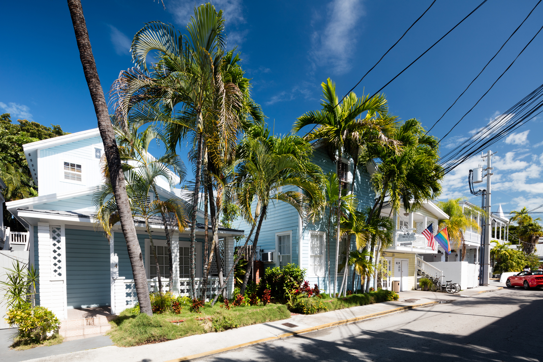 A line of houses in Key West, Florida, on a sunny day with palm trees out front.