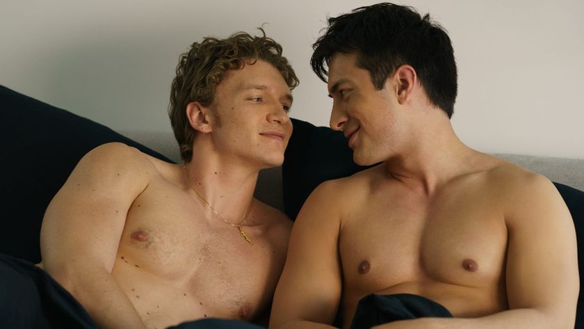 Ilya looking lovingly at Shane as they lay in bed without shirts on. 