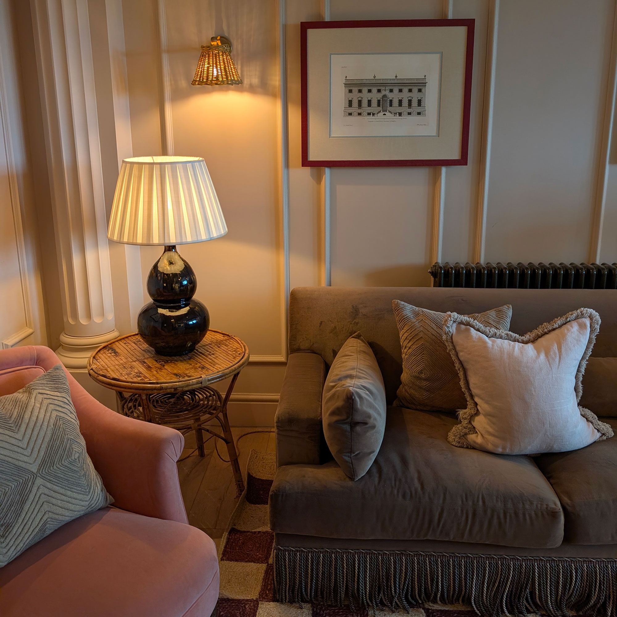 Corner of panelled room with sofa, armchair and side table with lamp