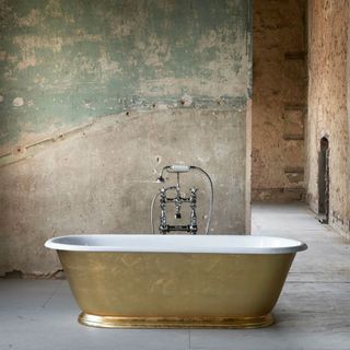 bathroom with golden bathtub and white tiled flooring