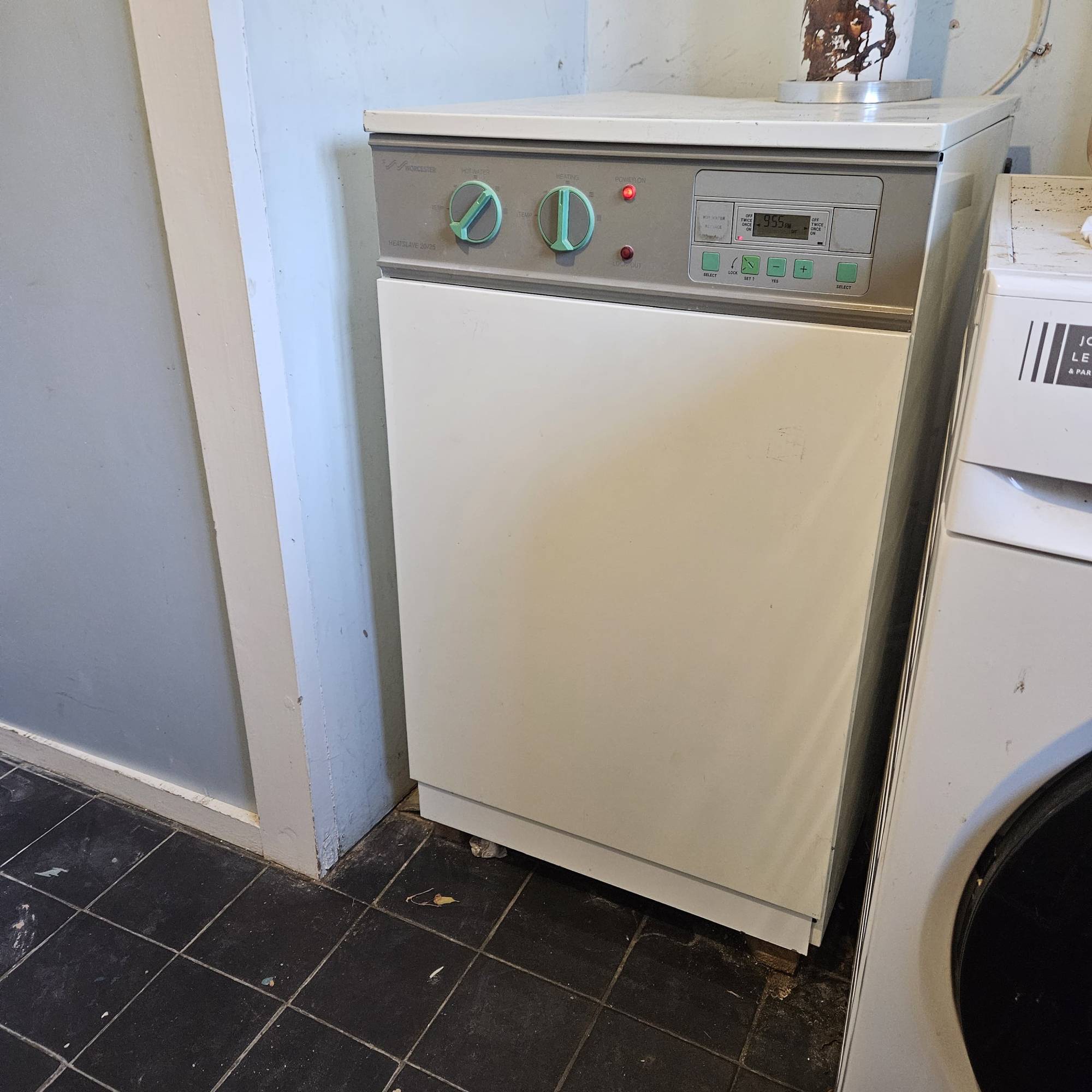 old oil boiler in utility room with airing cupboard with black tile