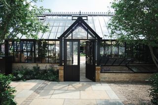 A Victorian glasshouse with a paved patio